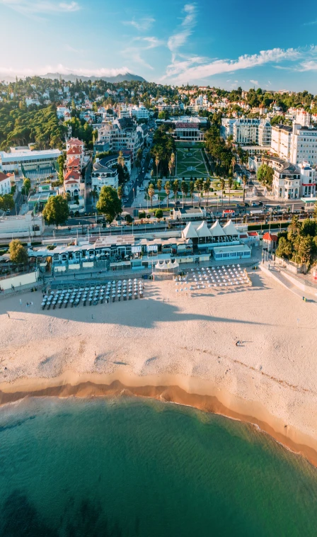 Vista a&eacute;rea de resort &agrave; beira-mar com praia, pr&eacute;dios e jardins ao p&ocirc;r do sol