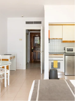 Cozinha e sala integradas, com porta de entrada e arm&aacute;rios claros