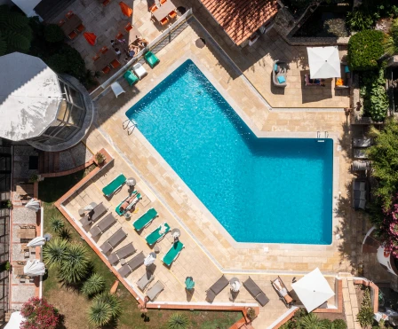 Piscina azul retangular em vista a&eacute;rea, com espregui&ccedil;adeiras e &aacute;reas externas.