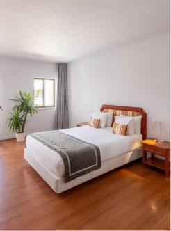 Quarto moderno com cama de casal e plantas ao lado da janela
