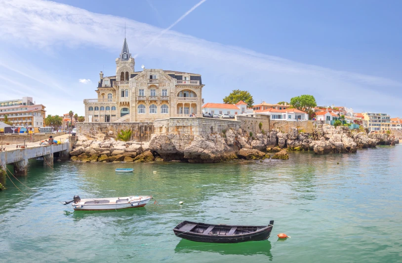 Edif&iacute;cio hist&oacute;rico &agrave; beira-mar com barcos na &aacute;gua azul.
