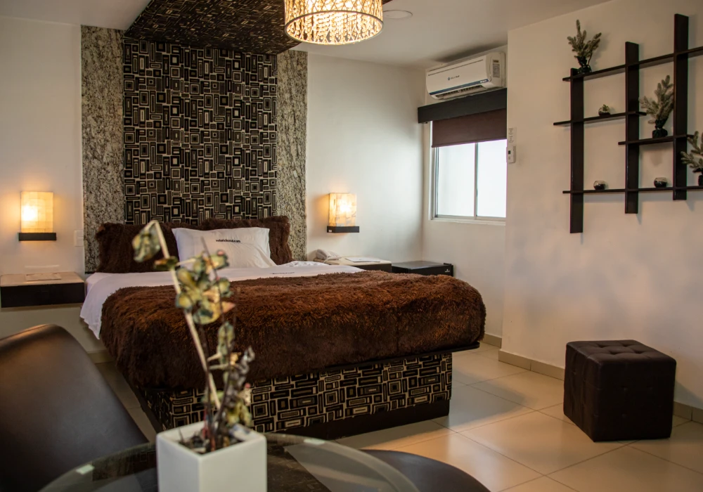 Dormitorio moderno con cama, l&aacute;mparas y paredes decoradas.