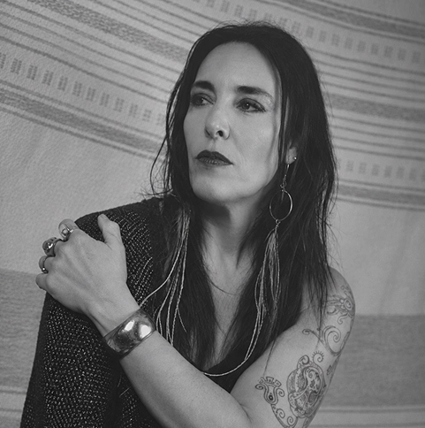 Black-and-white portrait of a woman with tattoos and long dark hair.