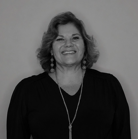 Portrait of a smiling woman with dangling earrings and necklace.