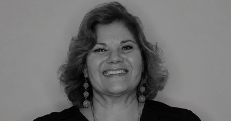 Smiling woman with curly hair and dangling earrings in a studio portrait