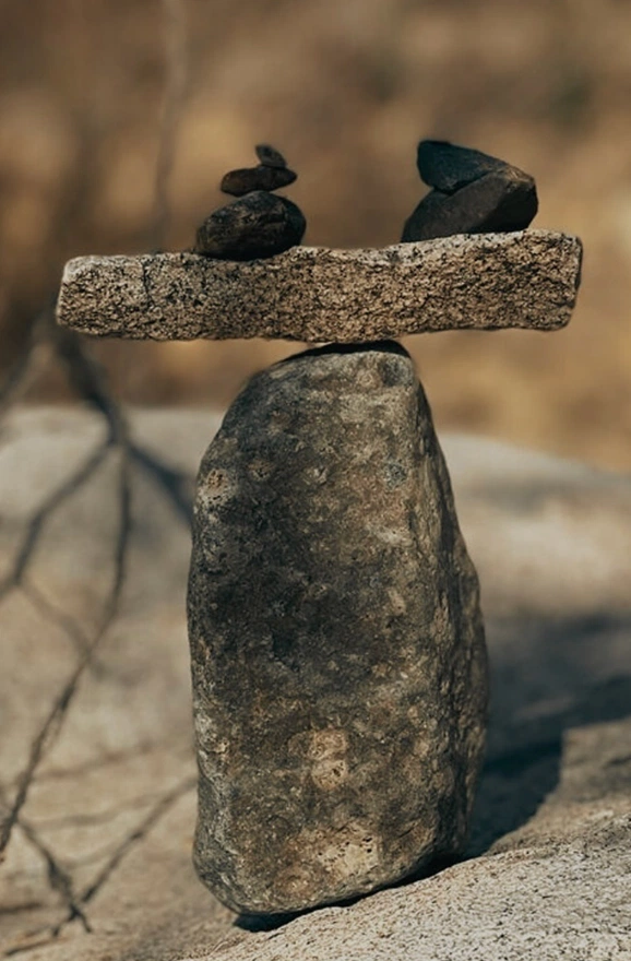 Stacked stone cairn with two balancing rocks in an outdoor setting