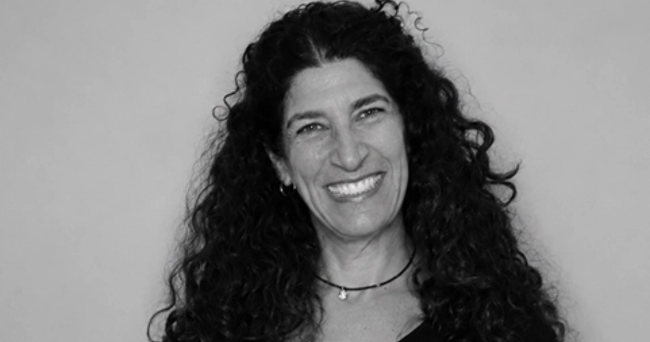 Smiling woman with long curly dark hair against a light background