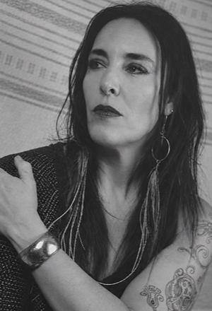 Black-and-white portrait of a woman looking to the side, wearing earrings.