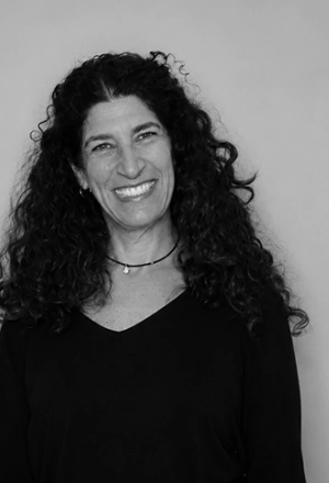 Smiling woman with curly hair against a plain light background