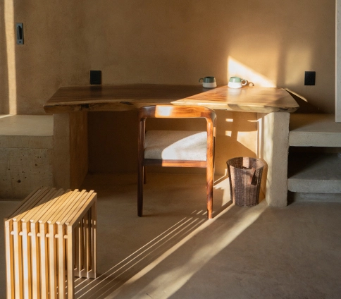 Minimalist room with wooden table, chair, and bright fireplace lighting.