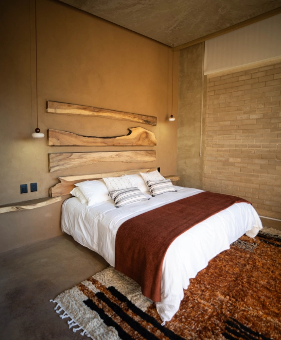 Cozy bedroom with white bedding, brown throw, and wooden wall art