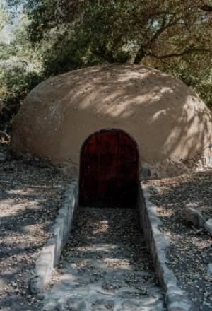 Stone oven with arched dark doorway in a rural outdoor setting