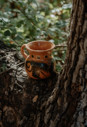 Terracotta pot with painted designs on a tree stump outdoors