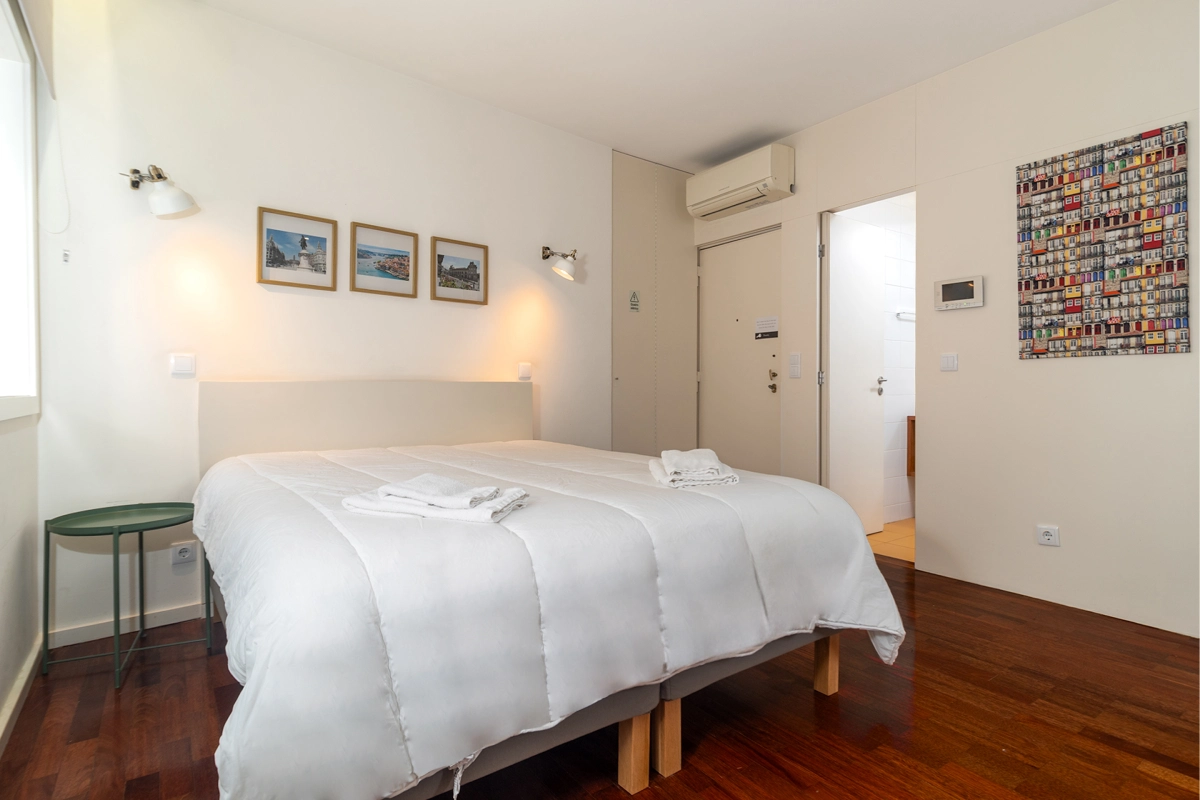 Dormitorio luminoso con cama doble, aire acondicionado y cuadros en pared