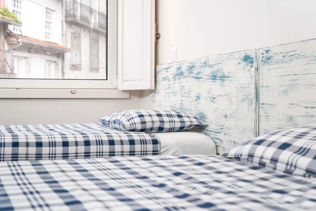 Habitaci&oacute;n con cama y almohadas a cuadros, pared azul con estampado marino