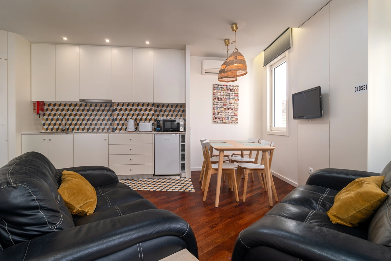 Sala moderna con sof&aacute;, mesa de comedor y cocina integrada, luminaria colgante