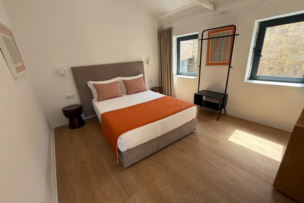 Dormitorio moderno con cama doble y mesa auxiliar, luz natural