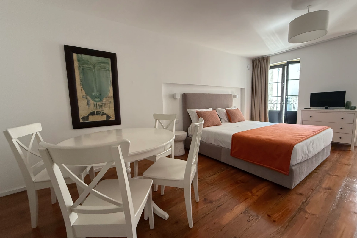 Dormitorio moderno con cama, mesa redonda, sillas y ventanas panor&aacute;micas