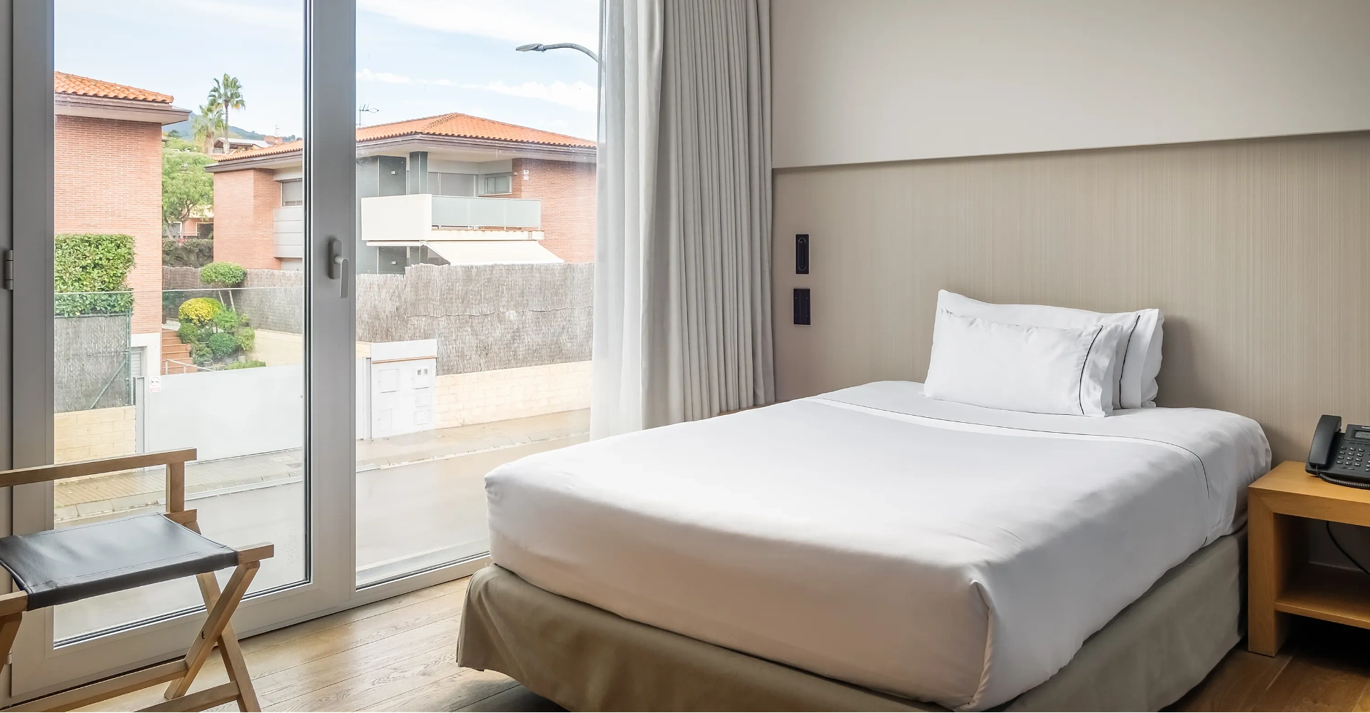 Habitaci&oacute; d&rsquo;hotel amb llit doble, finestra i cortines, vistes al pati.