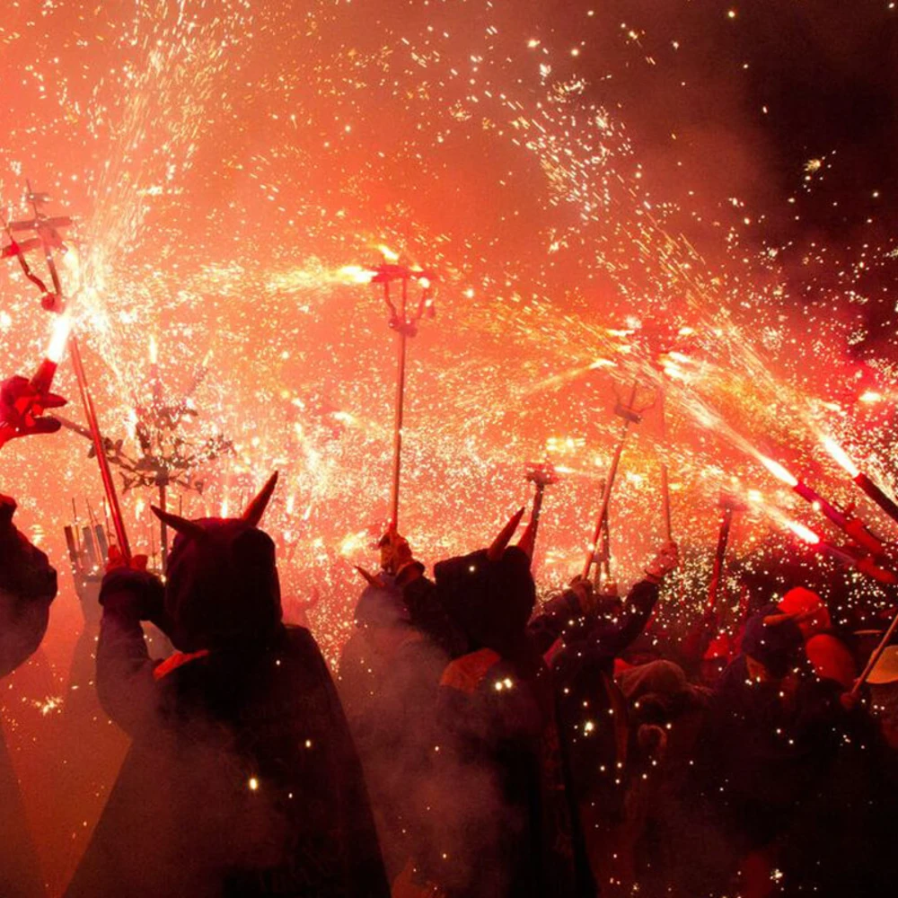 Multitud celebrando con confeti y bengalas en un concierto, luces rojas y chispas