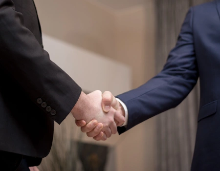 Dos personas estrechando manos en un entorno de oficina.