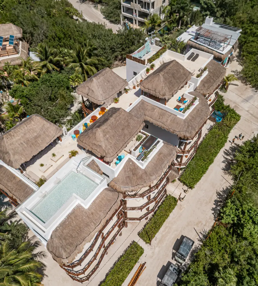 Vista a&eacute;rea de caba&ntilde;as con techo de palapa y piscina en un complejo vacacional