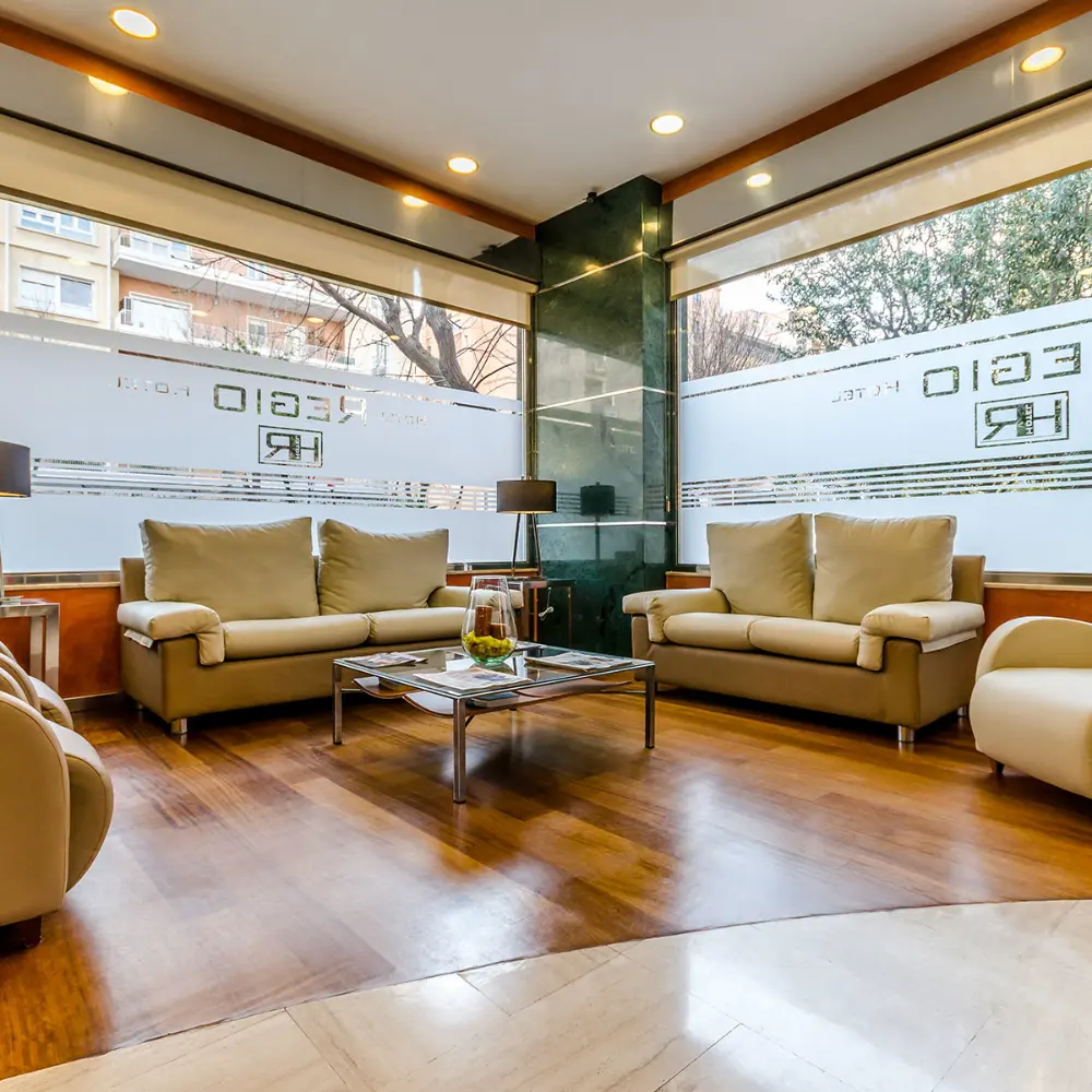 Sala de espera moderna con sof&aacute;s beige, mesa de centro y ventanales.