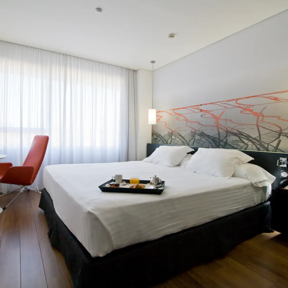 Dormitorio moderno con cama doble, sill&oacute;n rojo y l&aacute;mpara de techo
