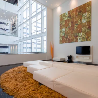 Sala moderna con sof&aacute; blanco, alfombra marr&oacute;n y panel art&iacute;stico en pared