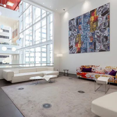 Sala moderna con sof&aacute; blanco, cuadros abstractos y ventanas grandes.