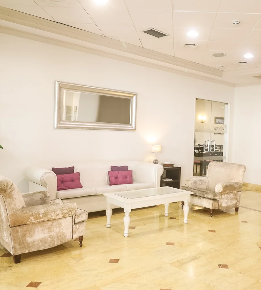 Sala de estar luminosa con sillones, sof&aacute; y mesa blanca en piso de m&aacute;rmol