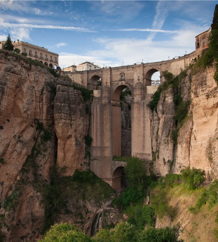 Puente de arcos y murallas sobre un ca&ntilde;&oacute;n, paisaje urbano al cielo azul