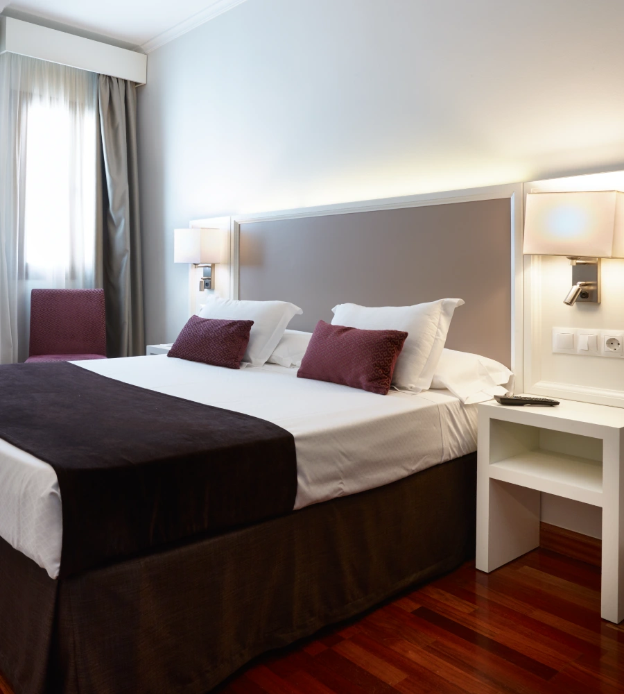 Dormitorio moderno con cama doble, mesillas y l&aacute;mparas de lectura