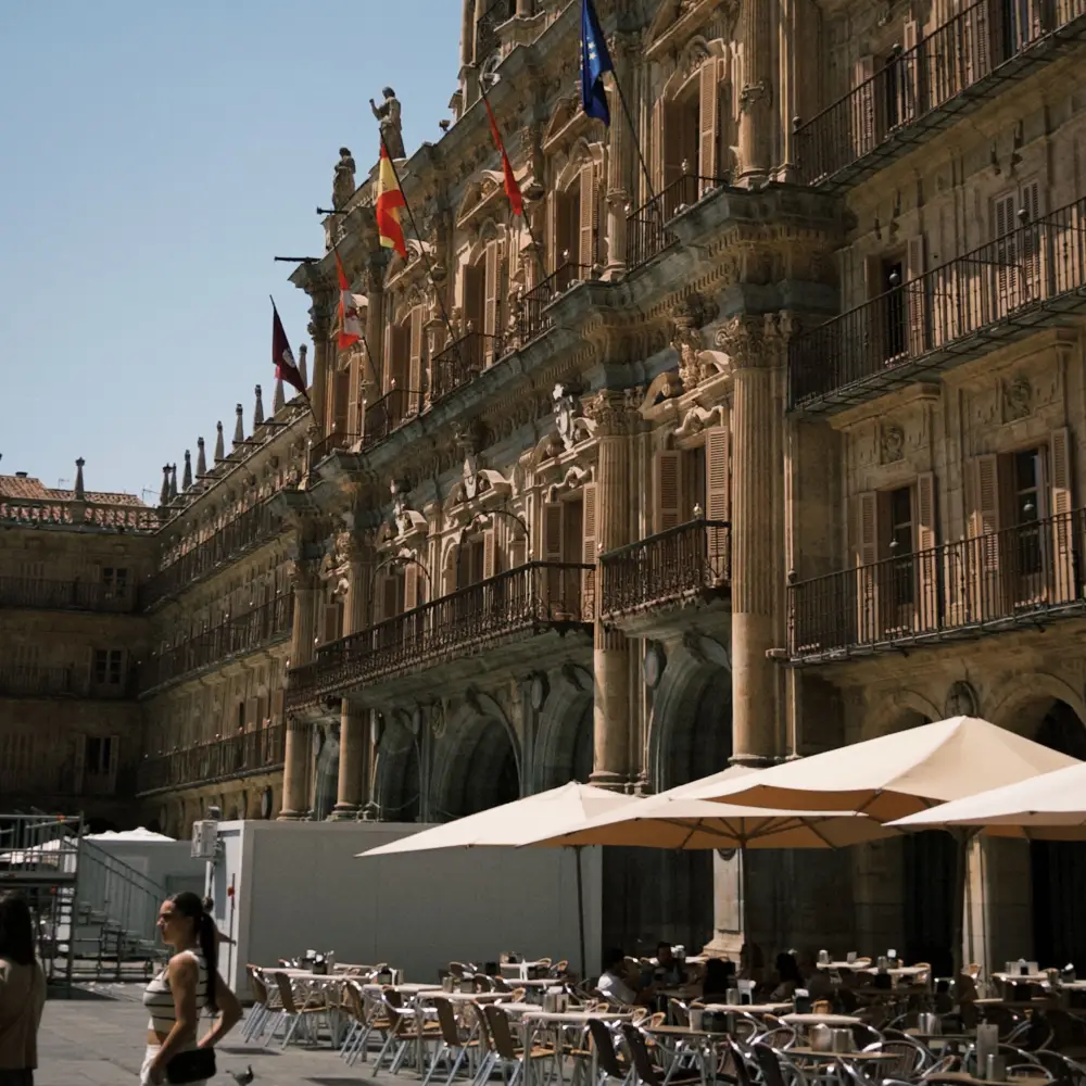 Terraza de hotel con banderas y fachada hist&oacute;rica de edificios al atardecer