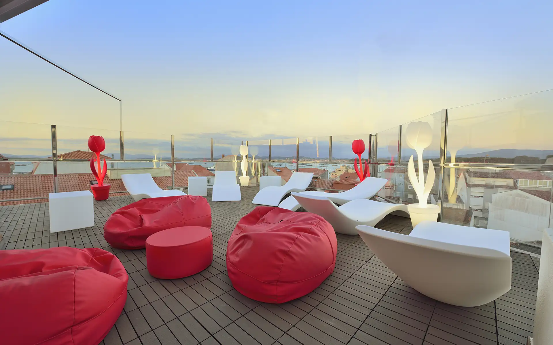 Terraza con sillones inflables rojos y blancos y cielo al atardecer.