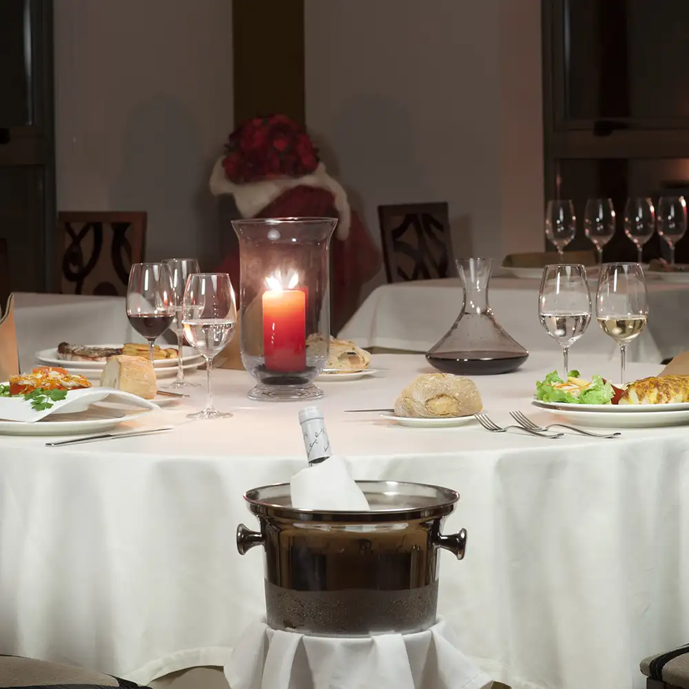 Mesa servida con velas encendidas, copas y platos en un banquete.