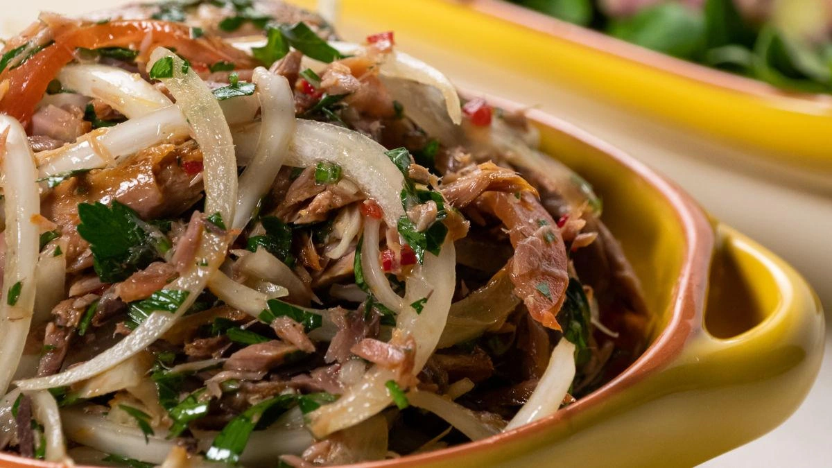 Salada de carne com cebola e ervas em tigela colorida