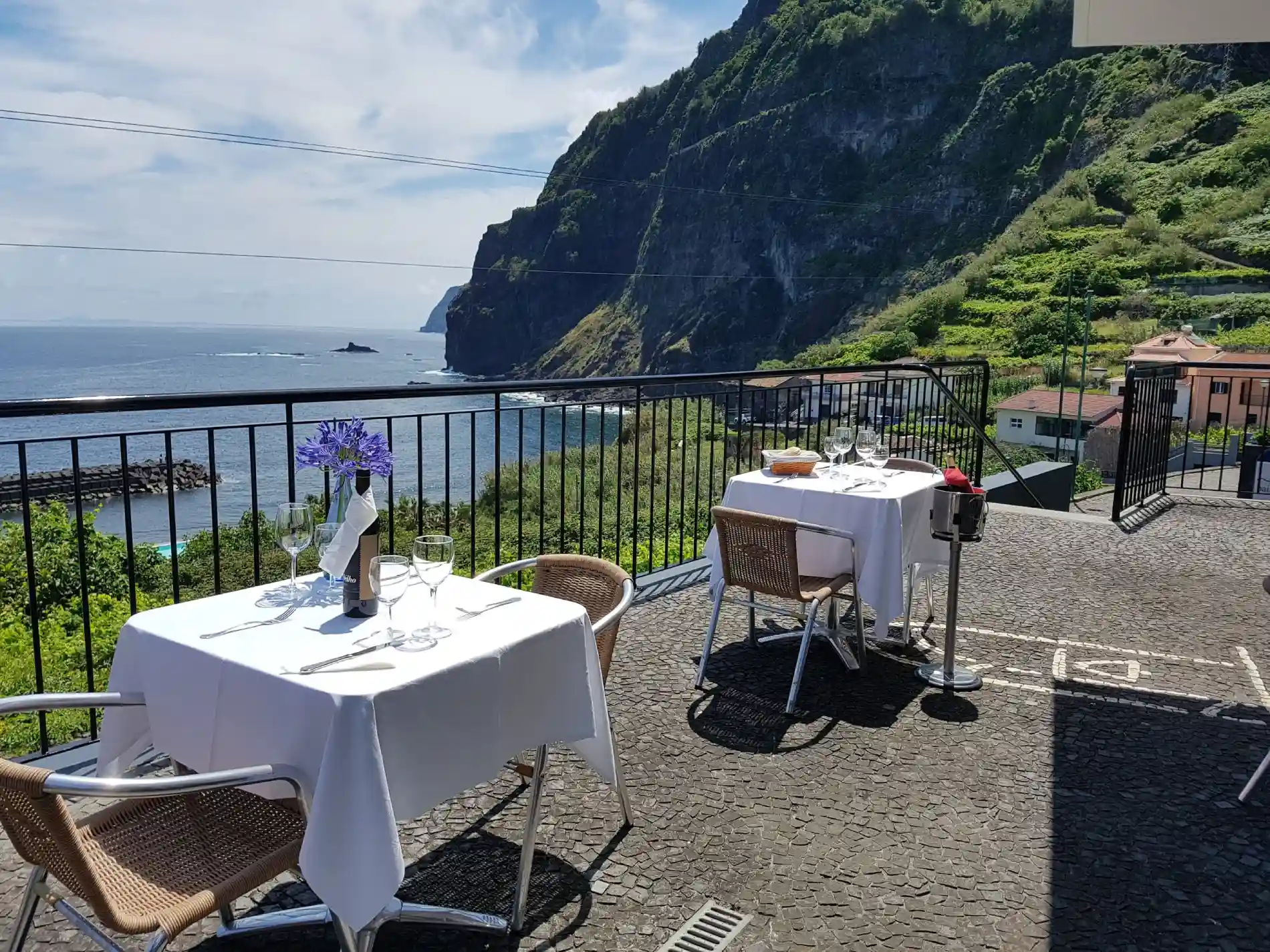 Mesa posta em terra&ccedil;o com vista do mar e montanha verde ao fundo