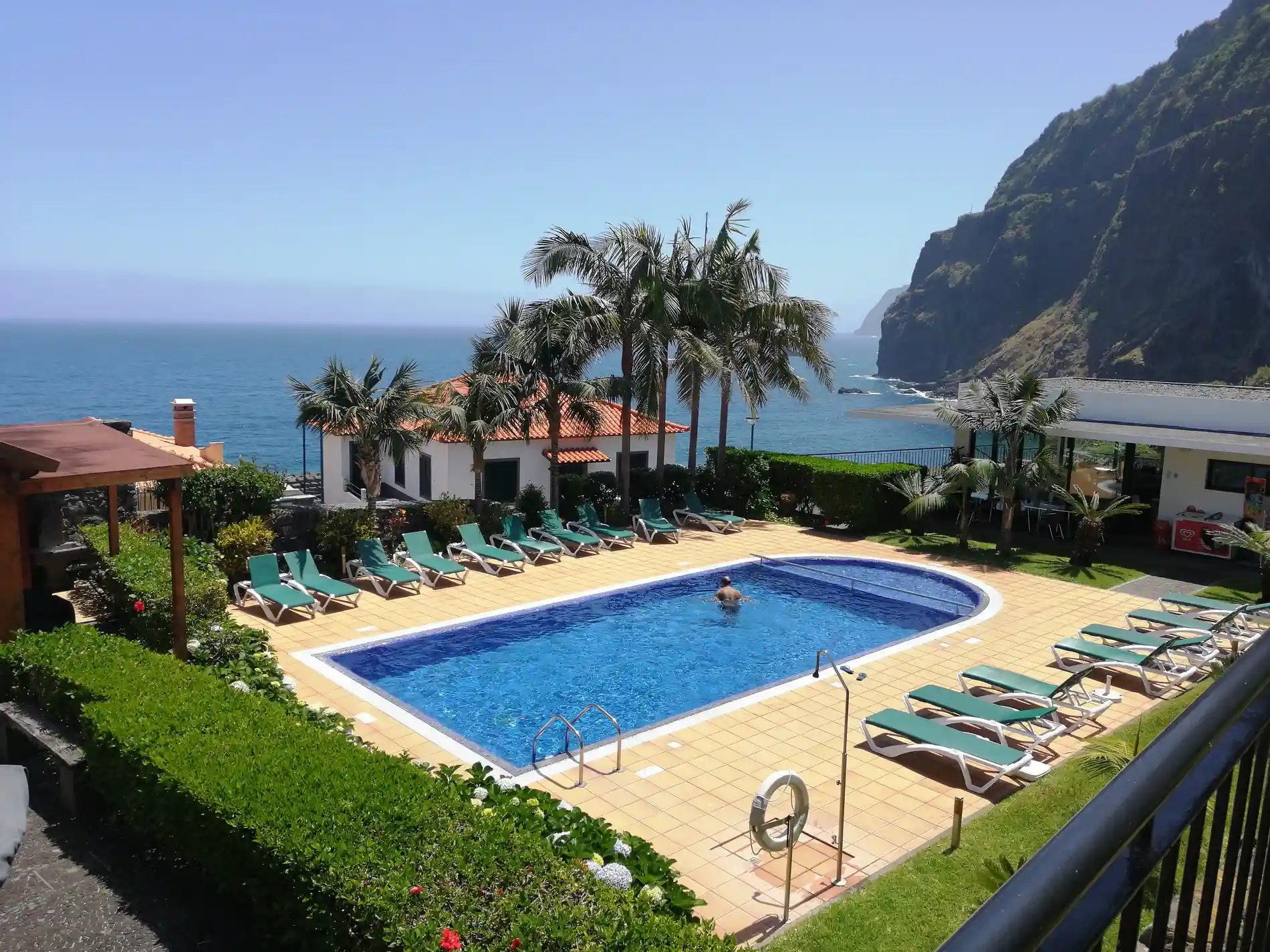Piscina com espregui&ccedil;adeiras e vista do mar e montanhas costeiras