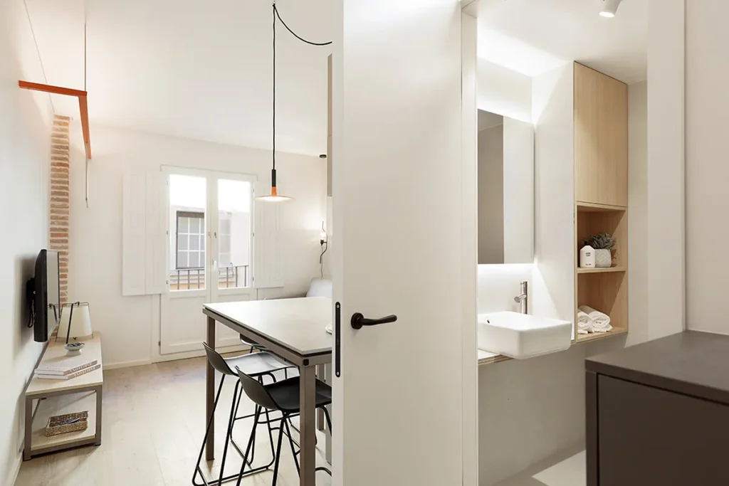 Cocina luminosa moderna con mesa, sillas y estanter&iacute;a de madera y lavabo