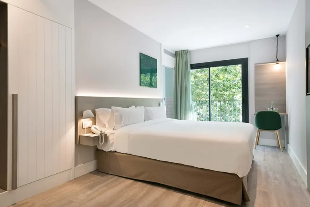 Dormitorio moderno con cama blanca, ventana y cortinas verdes, luz natural
