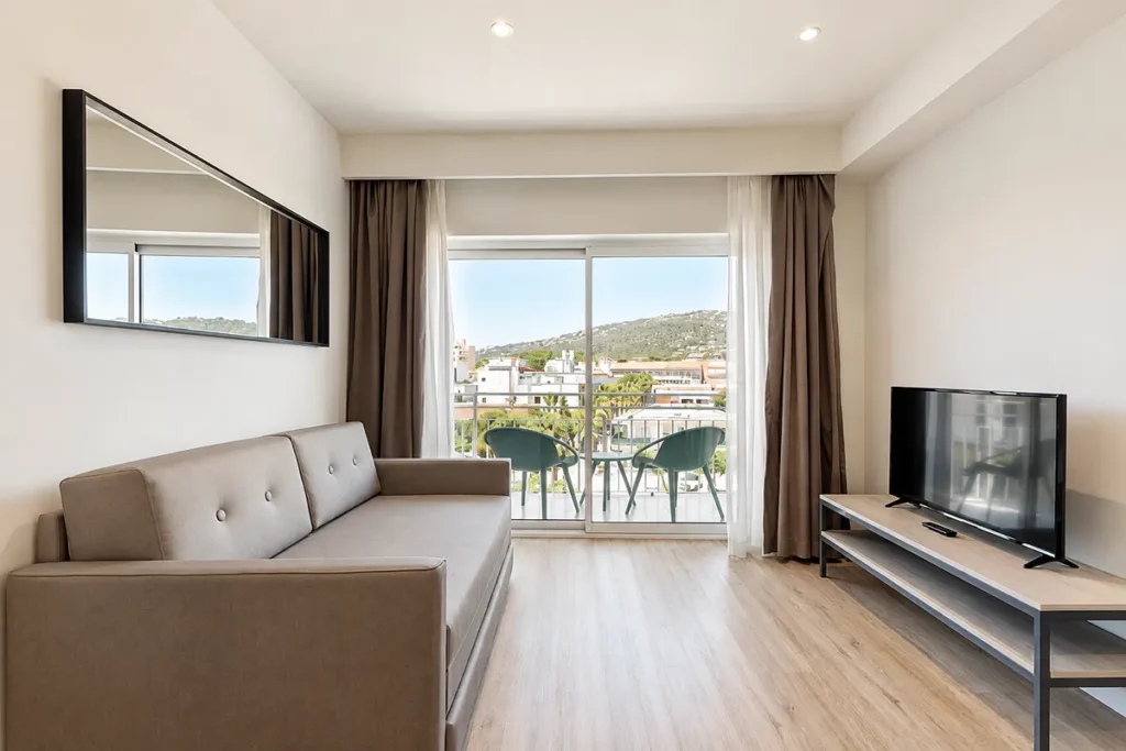 Sala de estar moderna con sof&aacute;, TV y ventanas al balc&oacute;n y monta&ntilde;as