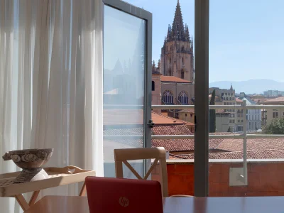 Vista desde hotel: silla y ventana con catedral al fondo en ciudad.