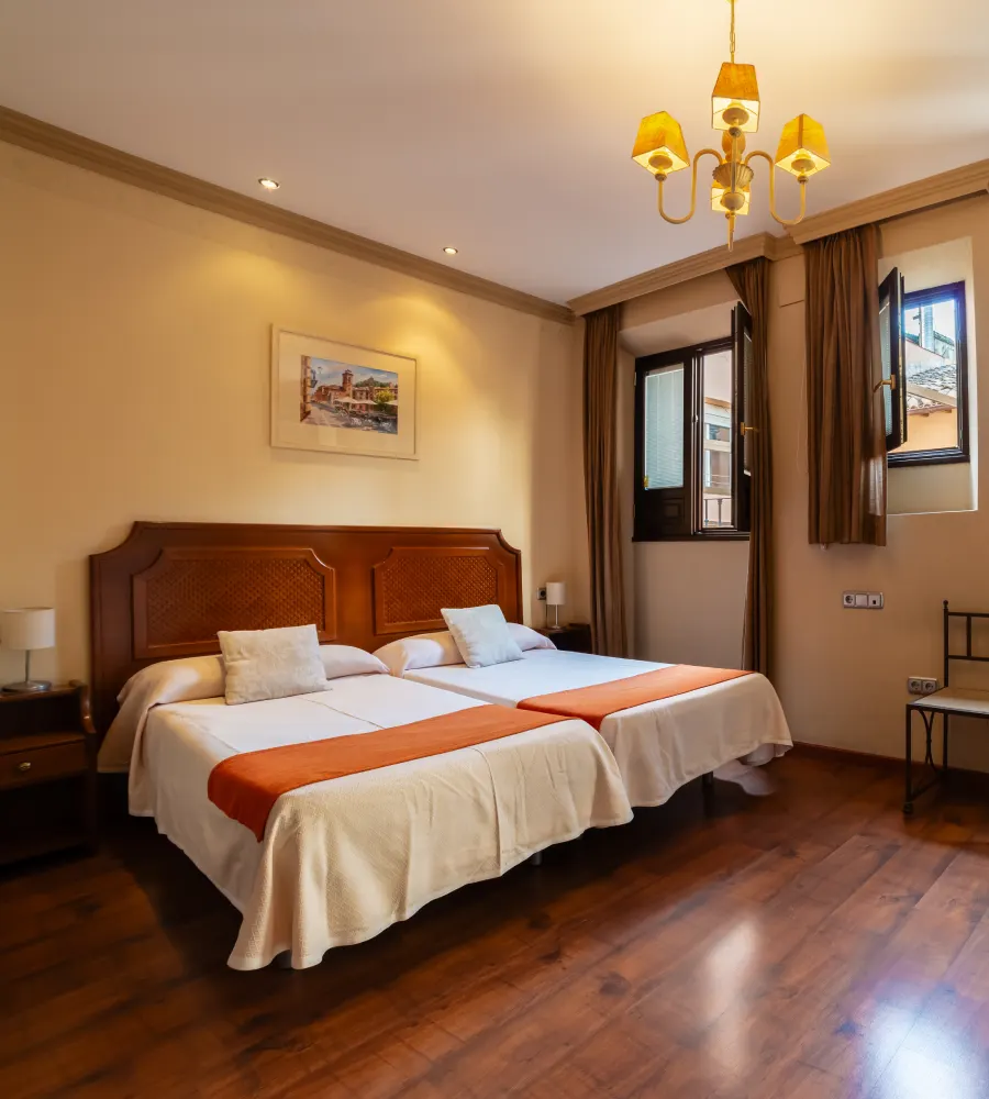 Dormitorio con cama doble, cortinas oscuras y l&aacute;mpara de ara&ntilde;a dorada