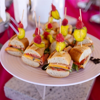Mini sandwiches on a platter with berry and lime appetizer skewers