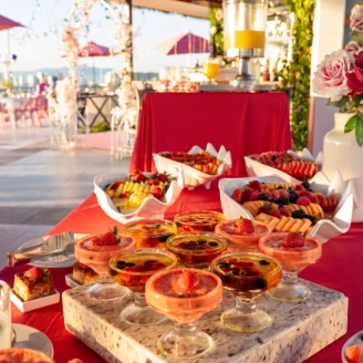 Outdoor catering table with pastries and desserts, red tablecloth and roses