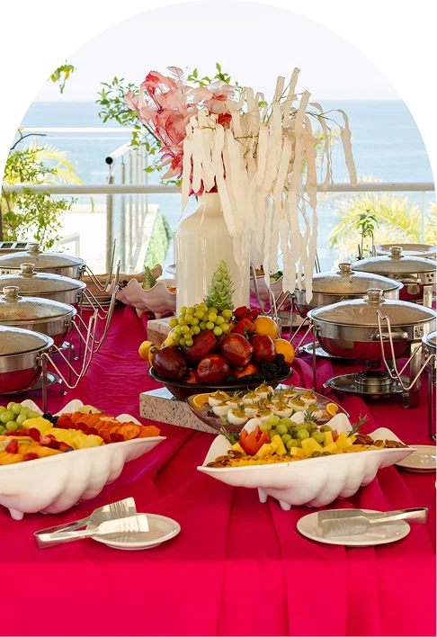 Wedding buffet table with fruit, desserts, flowers, and chafing dishes by sea