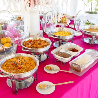 Buffet table with dishes and bowls at an outdoor event, bright pink cloth