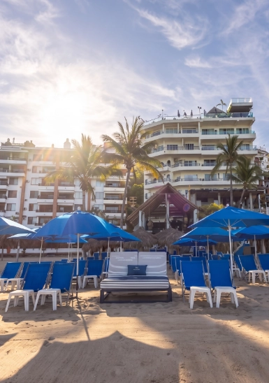Beach lounge chairs and umbrellas in front of a seaside hotel at sunset