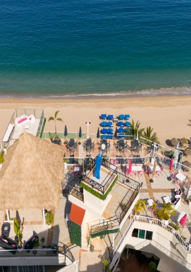 Aerial view of a beachfront resort with pool, umbrellas, and sandy shoreline